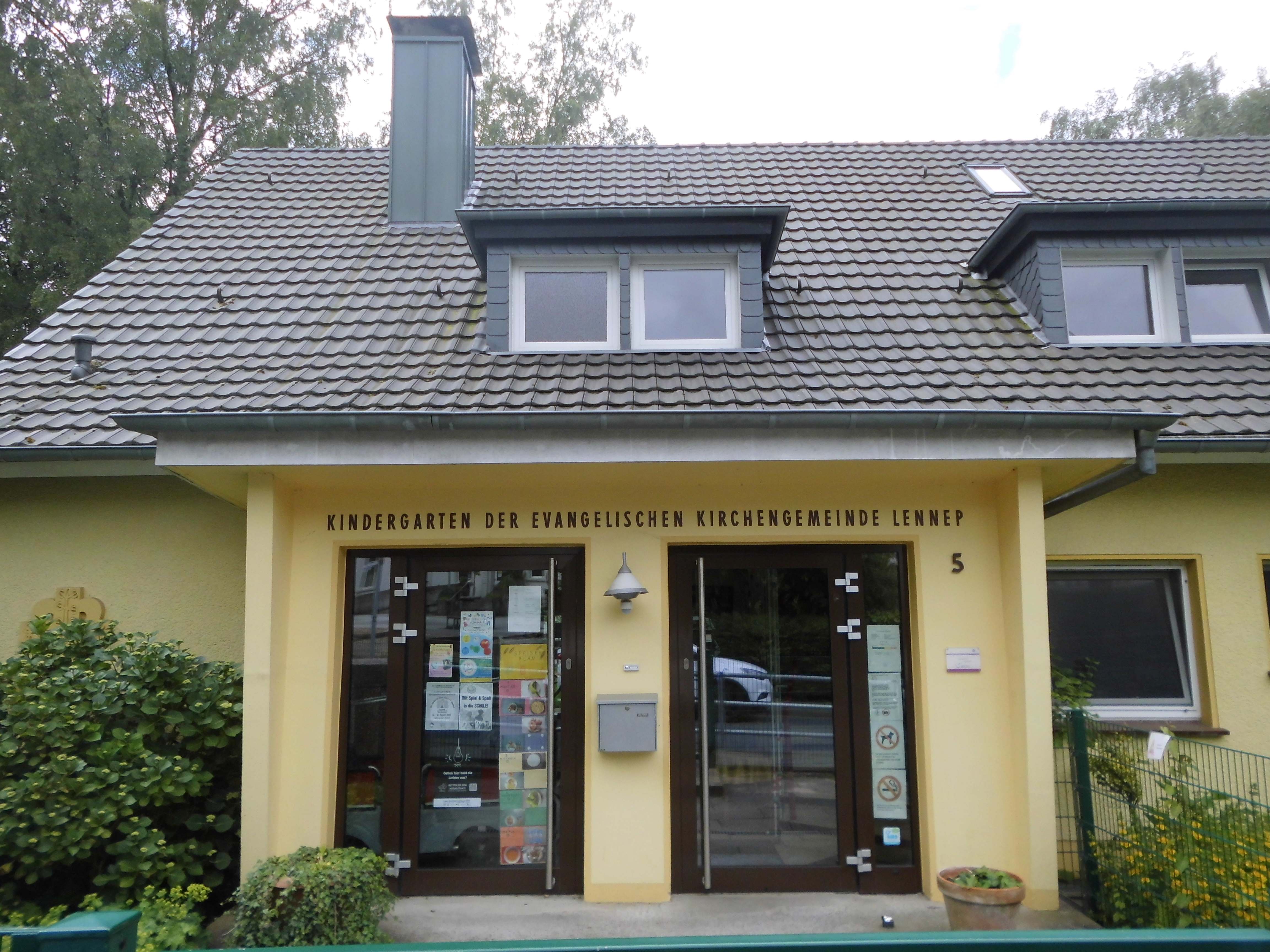 Ein einladendes gelbes Haus mit Glasfenster und großer Glastür eingerahmt von grünen Stauden.